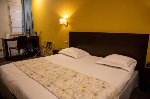 a bedroom with a large bed with two pillows at Grand Hôtel d'Orléans in Toulouse