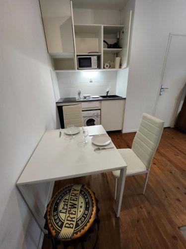 - une table et des chaises blanches dans une petite cuisine dans l'établissement Agréable et vaste Studio à 350 M de Paris, à Gentilly