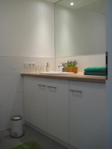 a white bathroom with a sink and a mirror at Jordanshof Grün in Xanten