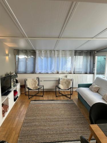 un salon avec un canapé et deux chaises dans l'établissement Maison cosy et jardin verdoyant, à Drancy