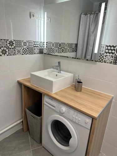 une salle de bain avec une machine à laver et un lavabo dans l'établissement Super logement familial, au Grau-du-Roi