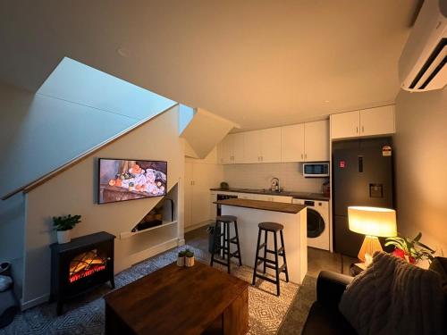 a living room with a fireplace and a kitchen at Devonport CBD Modern Loft in Devonport