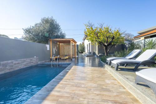 AsgourouにあるCity Art Villaのラウンジチェア付きのスイミングプールが隣接しています。