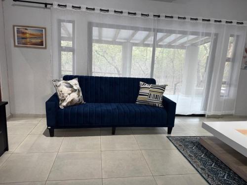 a blue couch in a living room with a window at Royal On Olifant Drive in Marloth Park
