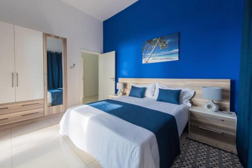 a blue bedroom with a large bed with blue walls at Riva Sagara by IHR in Flic-en-Flac