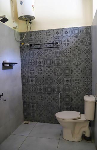 a bathroom with a toilet and a tile wall at Himkosi Farm by the River in Almora