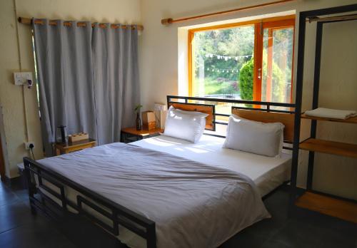 a bedroom with a bed with two pillows and a window at Himkosi Farm by the River in Almora