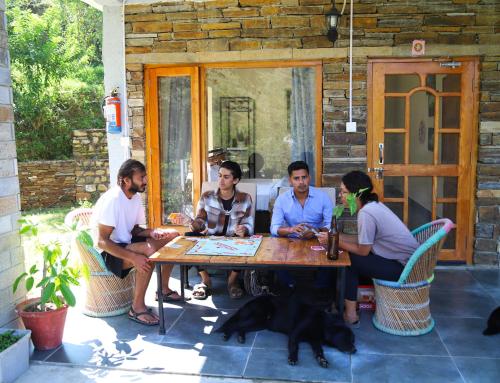 a group of people sitting around a wooden table at Himkosi Farm by the River in Almora