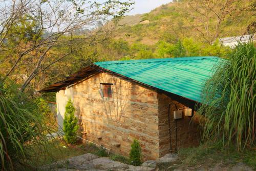 a small brick building with a green roof at Himkosi Farm by the River in Almora