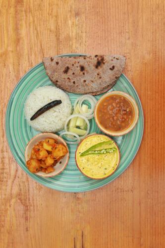a plate of food with rice and bread on a table at Himkosi Farm by the River in Almora