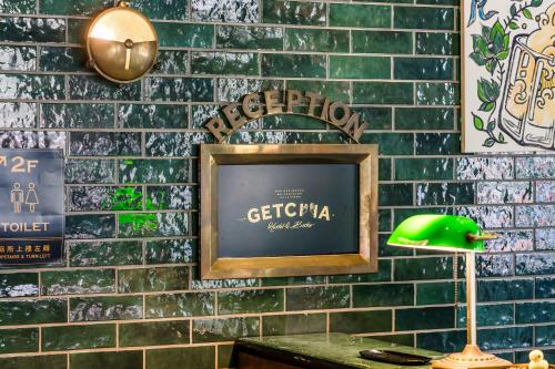 a television on a brick wall with a green lamp at Getcha Hostel in Taichung