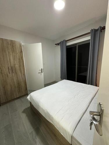 a bedroom with a white bed and a window at Mayor Condusive Apartments in Flic-en-Flac