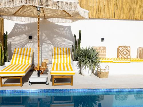 two chairs and an umbrella next to a swimming pool at Unique Beachside Studio, Shared Pool & Burj Khalifa View! in Dubai