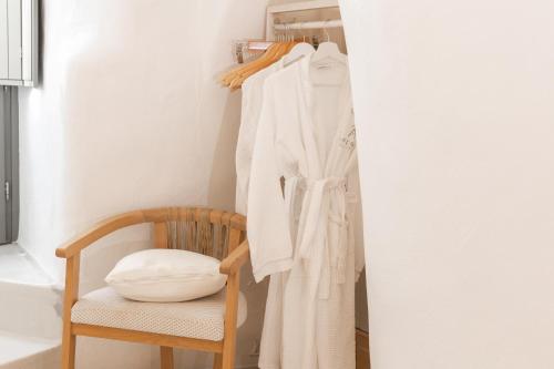 a closet with a chair and a robe at Aperto Suites - Adults Only in Fira
