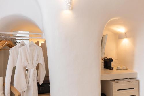 a dressing room with white coats hanging on a rack at Aperto Suites - Adults Only in Fira