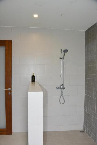 a shower in a bathroom with a white wall at 2 Bedroom Villa with Pool & Close to Setangi Beach in Mangsit