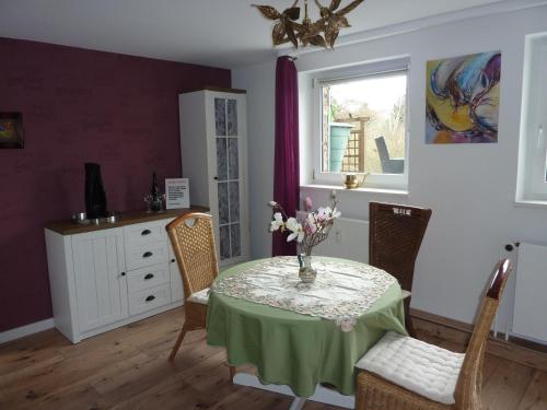 a dining room with a table with a vase of flowers on it at Rosi's Kuschelapartment in Geisenheim
