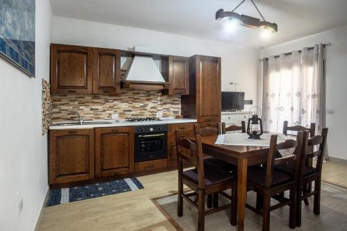 a kitchen with wooden cabinets and a table with chairs at Su Giuali in SantʼAnna Arresi