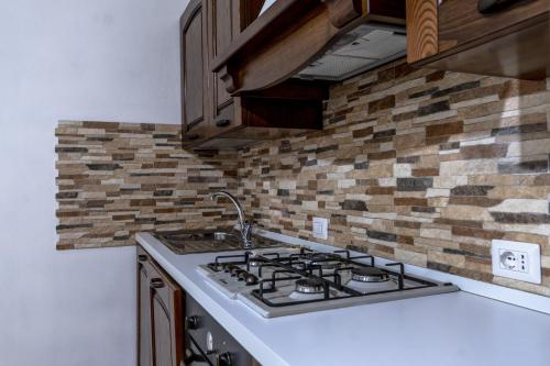 a kitchen with a stove top oven next to a brick wall at Su Giuali in SantʼAnna Arresi