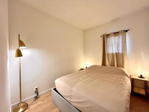 une chambre avec un lit blanc et une lampe dans l'établissement Le Petit Prince de Maïmo, à Sainte-Maxime