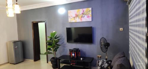 a living room with a blue wall with a flat screen tv at Cardinal Green Apartments in Lagos