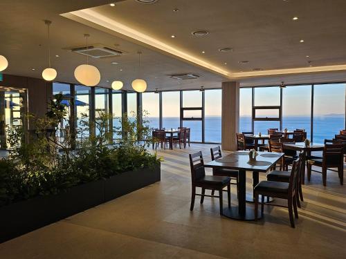 a restaurant with tables and chairs and a view of the ocean at PANAQ operated by SONO in Yeongdeok