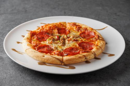 a pepperoni pizza on a white plate on a table at The Royal Park Canvas - Osaka Kitahama in Osaka