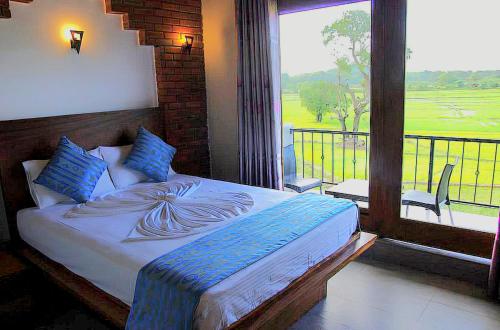 a bedroom with a bed and a large window at Peacock Eco Resort Sigiriya in Sigiriya