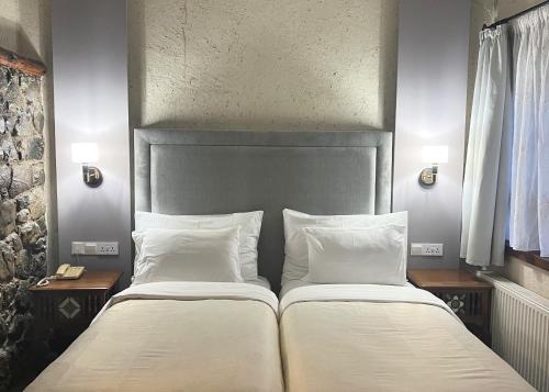 two beds with white sheets and pillows in a bedroom at The Mill Hotel in Kakopetria