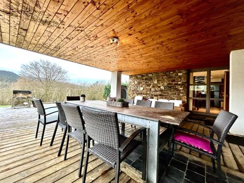 eine Terrasse mit Tisch und Stühlen auf einem Deck in der Unterkunft Le Ny d'Ange in Stoumont