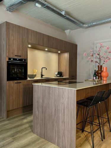 a kitchen with wooden cabinets and a counter with stools at Loft Apartment City Stay & Go Enschede in Enschede
