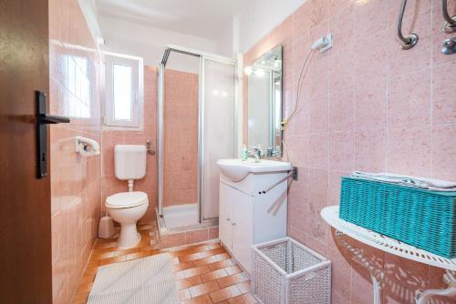 Baño de color rosa con aseo y lavamanos en Ivy Apartments in Center, en Novalja