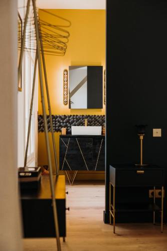 La salle de bains est pourvue d'un mur jaune et d'un miroir. dans l'établissement Château de Neyran chambre d'hôtes & Spa, à Soulac-sur-Mer