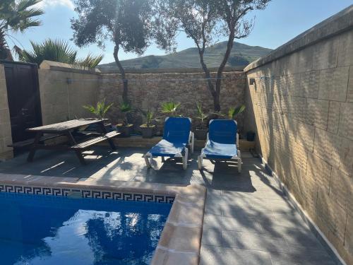 a patio with two chairs and a table next to a pool at 4 Bedroom Holiday Home with Private Pool in Għarb
