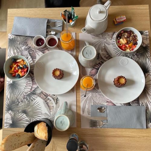 Una mesa con platos de comida y bebidas sobre ella. en Château de Neyran chambre d'hôtes & Spa, en Soulac-sur-Mer