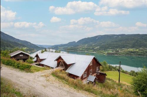 a group of barns on a hill next to a river at Historic Farm With Panoramic Views In Gudbrandsdalen in Favang