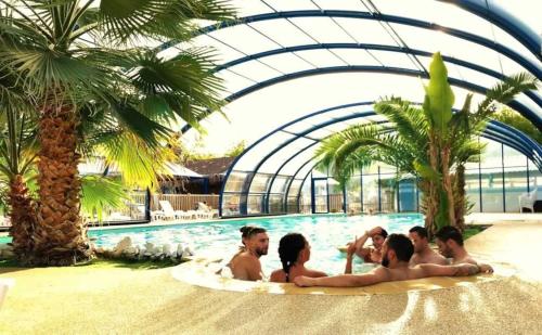a group of people in a swimming pool with palm trees at Camping 4 étoiles - Piscine - eecaad in Aureilhan