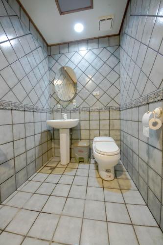 a tiled bathroom with a toilet and a sink at Songyuan B&B in Lugu