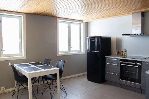 a kitchen with a table and a black refrigerator at Huoneisto viehättävällä puutaloalueella in Uusikaupunki