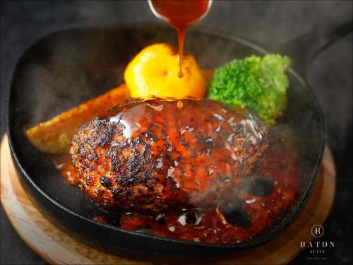 a plate of food with meat and broccoli and sauce at BATON SUITE Okinawa-kourijima in Nakijin