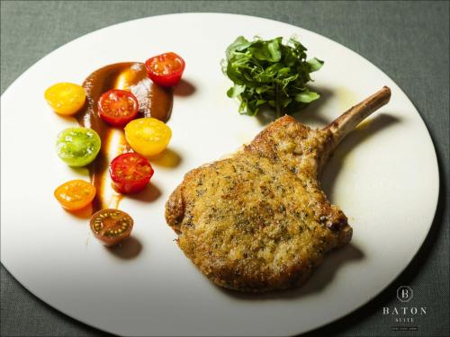 a white plate with a piece of meat and vegetables at BATON SUITE Okinawa-kourijima in Nakijin
