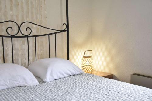 - une chambre avec un lit doté d'oreillers blancs et d'une lampe dans l'établissement Appartement 2 pièces - Gruissan GN580-028, à Gruissan