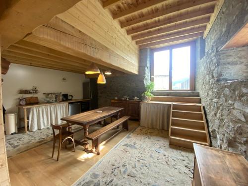 - une cuisine avec une table en bois et un mur en pierre dans l'établissement Gîte de Montagne, à Aragnouet
