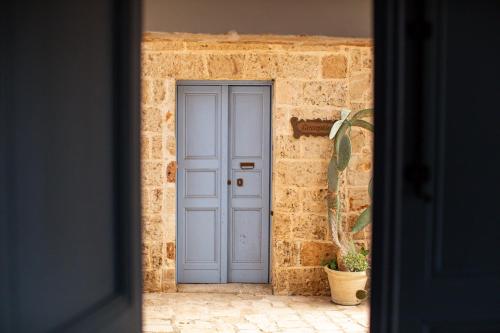 a blue door in a brick wall with a potted plant at Masseria La Tofala benessere & SPA in Copertino