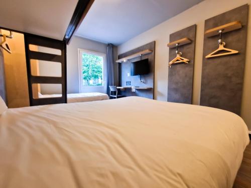 a bedroom with a large white bed and hangers at ibis Budget Lille Marcq En Baroeul in Marcq-en-Baroeul