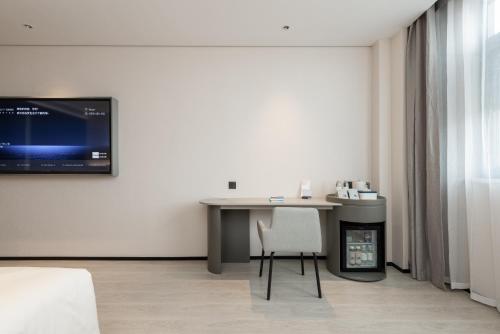 a room with a desk and a tv on a wall at Atour Hotel Wuxi Meili Ancient Town Jinglong Plaza in Wuxi