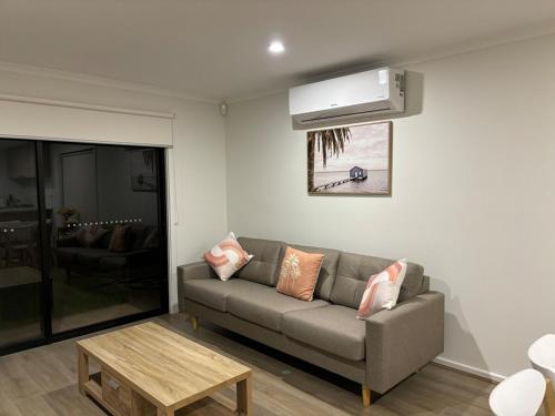 a living room with a couch and a air conditioner at Sunflower Homes- Light and Easy in Munno para Downs