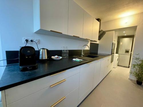 a kitchen with white cabinets and a black counter top at BnGo I Le Spacieux I 12 personnes, 5 chambres, 2 salle de bain, parking privé, WC séparé, Wifi in Villeurbanne