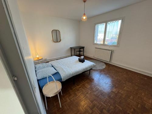 a bedroom with a bed and a table and a window at 120m T4 terrasse et parking - Stade-Eurexpo-Lyon in Meyzieu