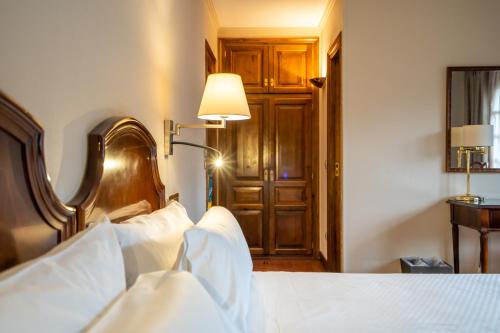 a bedroom with a bed with white sheets and a lamp at Abba Xalet Suites Hotel in Sispony